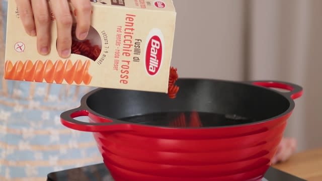 Pouring Barrila red lentil pasta into pot