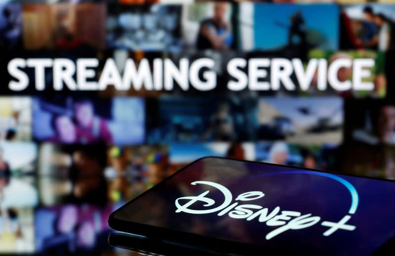 FILE PHOTO: Smartphone with displayed "Disney" logo is seen in front of displayed "Streaming service" words in this illustration