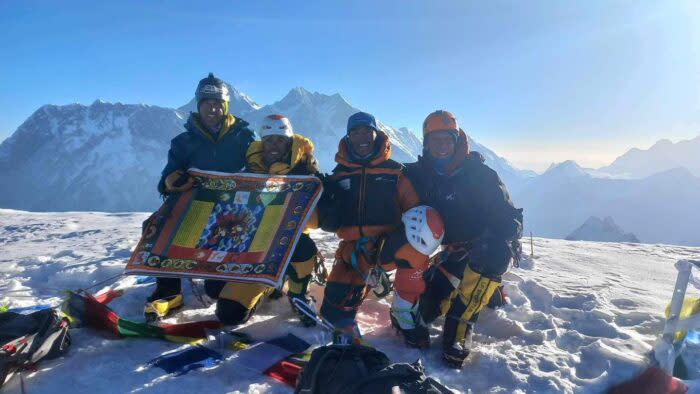 four climbers on the flat summit of Ama Dablam early in the morning.