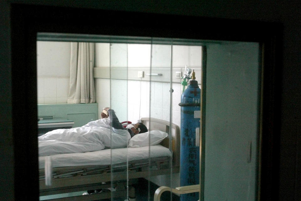 Image: A SARS patient receives treatment behind double-layer glass windows at a hospital in Beijing on April 13, 2003. (Ng Han Guan / AP file)