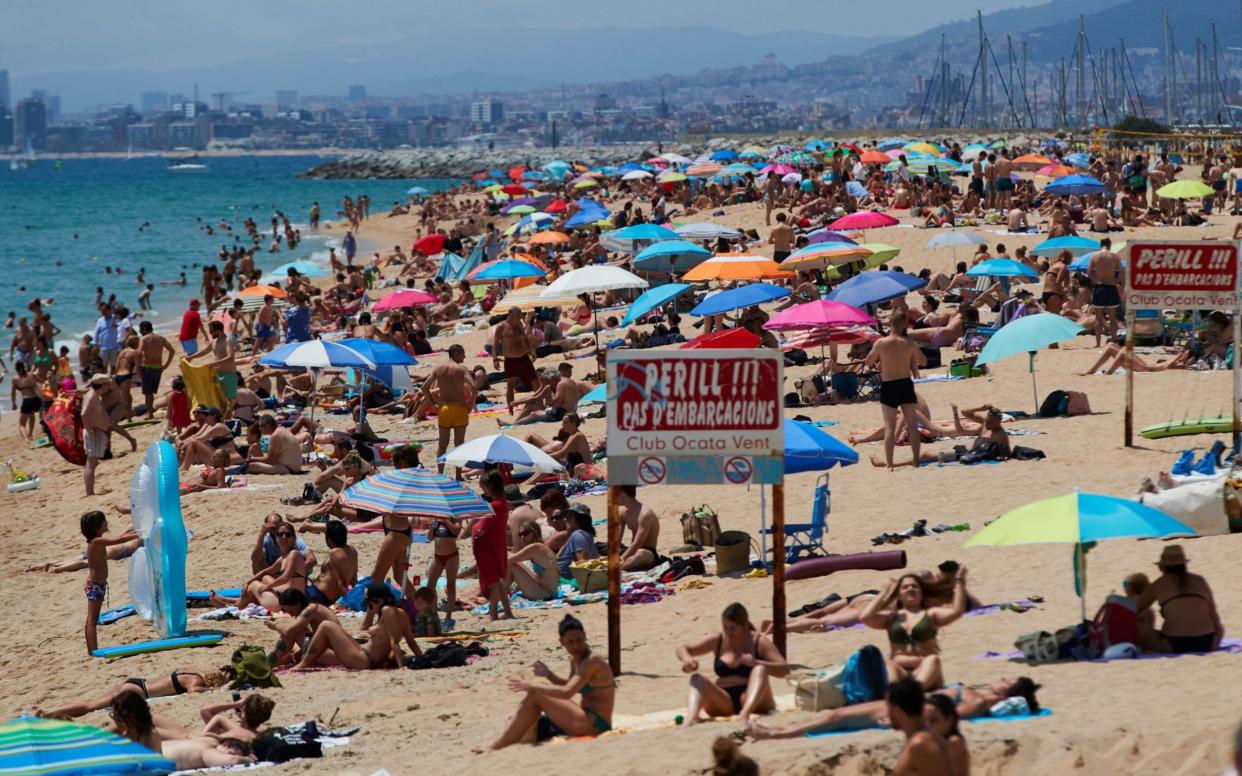 People enjoy sunny weather at the beach, Barcelona, Spain - Shutterstock