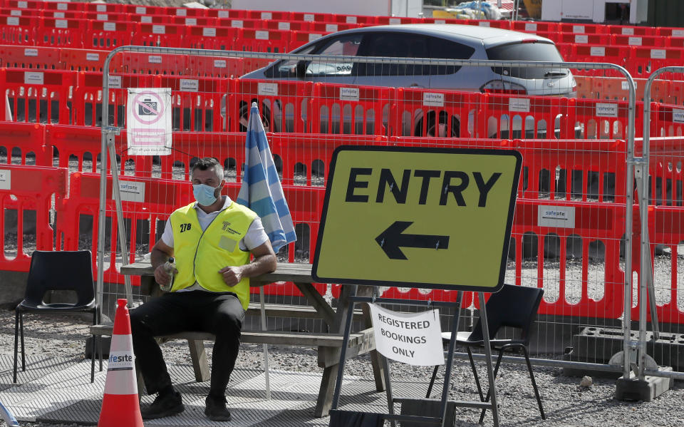 A staff member waits at the entrance to nearly empty lanes of a Covid-19 drive thru testing facility at Twickenham stadium in London, Thursday, Sept. 17, 2020. Britain has imposed tougher restrictions on people and businesses in parts of northeastern England on Thursday as the nation attempts to stem the spread of COVID-19, although some testing facilities remain under-utilised. (AP Photo/Frank Augstein)