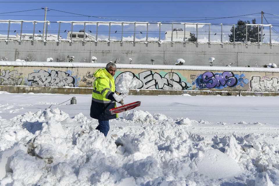 A worker shovel at a motorway after a snowstorm, in Athens, on Tuesday, Jan. 25, 2022. Army and fire service teams were deployed late Monday to extract hundreds of motorists trapped for hours in snowed-in cars. A snowstorm of rare severity disrupted road and air traffic Monday in the Greek capital of Athens and neighboring Turkey's largest city of Istanbul, while most of Greece, including — unusually — several Aegean islands, and much of Turkey were blanketed by snow. (AP Photo/Michael Varaklas)