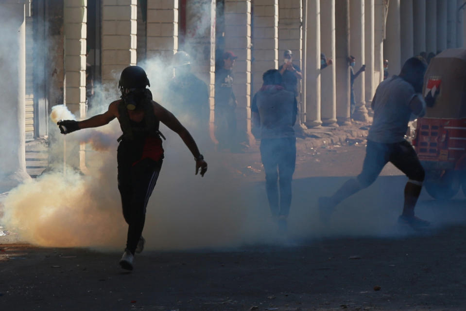 An anti-government protester prepares to throw a tear gas canister fired by Iraq security forces during clashes in the al-Rasheed street in Baghdad, Iraq, Friday, Nov. 8, 2019. The demonstrators complain of widespread corruption, lack of job opportunities and poor basic services, including regular power cuts despite Iraq's vast oil reserves. They have snubbed limited economic reforms proposed by the government, calling for it to resign. (AP Photo/Khalid Mohammed)