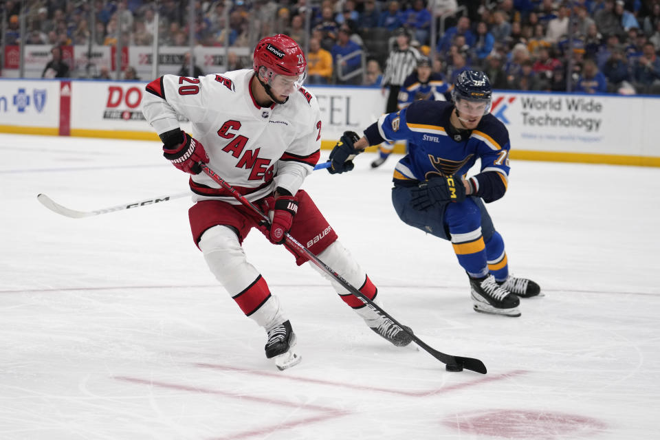 Carolina Hurricanes' Sebastian Aho (20) handles the puck as St. Louis Blues' Zack Bolduc (76) defends during the second period of an NHL hockey game Friday, April 12, 2024, in St. Louis. (AP Photo/Jeff Roberson)