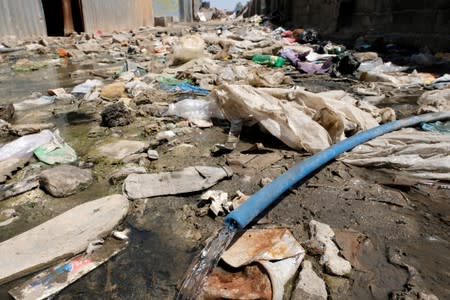 Water flows from a broken water pipe among the garbage at a displaced camp in Benghazi