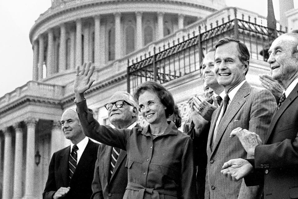 FILE - Sandra Day O'Connor waves after her unanimous confirmation by the U.S. Senate to the Supreme Court on Capitol Hill in Washington, D.C. in this Sept. 21, 1981 photo. Standing with O'Connor, from left to right, are: Attorney General William French Smith, Sen. Barry Goldwater, R-Ariz., Sen. Dennis DeConcini, D-Ariz., Vice President George Bush, and Senate Judiciary Committee Chairman Sen. Strom Thurmond, R-S.C. (AP Photo/J. Scott Applewhite, File)