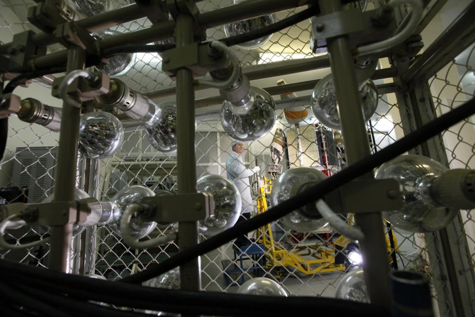 Head of an electrical testing laboratory Oleg Trifonov makes preparations before simulating sunlight by means of forty 1000-watt lamps while working on a Gonets-M low-orbital communication space satellite inside an assembly workshop of the Reshetnev Information Satellite Systems company in the Siberian town of Zheleznogorsk, some 50 km (31 miles) northeast of Krasnoyarsk, April 2, 2014. Picture taken April 2, 2014. REUTERS/Ilya Naymushin (RUSSIA - Tags: SCIENCE TECHNOLOGY BUSINESS)