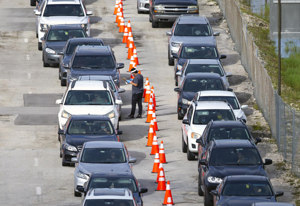 Vehicles line up as a healthcare workers help check people in as they are being tested at the COVID-19 drive-thru testing center at Hard Rock Stadium in Miami Gardens, Fla. on Wednesday, Oct. 28, 2020. (David Santiago/Miami Herald via AP)