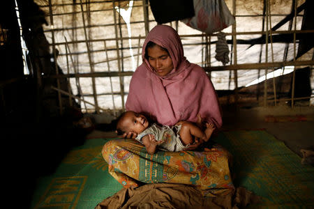 Jamalida, 30, holds her two-month-old daughter Shahida as she poses for a photograph inside their shelter in Kutupalang unregistered refugee camp in Cox’s Bazar, Bangladesh, February 10, 2017. REUTERS/Mohammad Ponir Hossain