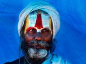 A Hindu holy man stands in the backdrop of a tent during the annual Magh Mela festival at Sangam, the confluence of rivers Ganges and Yamuna, in Allahabad, India, Wednesday, Jan. 19, 2011. Hundreds of thousands of Hindu pilgrims take dips in the confluence, some hoping to wash away sins and others to secure a fine spouse during the month long festival. (AP Photo/Rajesh Kumar Singh)