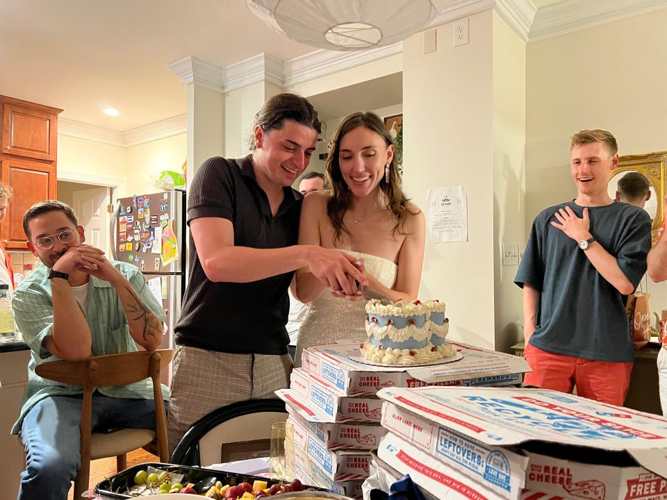 The couple cut their cake atop a pile of Domino's boxes.