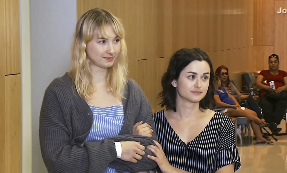 This photo taken from video provided by KGO-TV shows Brynn Ota-Mathews, 23, left, and Gabriella Gaus, 26, both wounded in the mass shooting at the Gilroy Garlic Festival, as they talk about their experience at Santa Clara Valley Regional Medical Center in Santa Clara, Calif., Thursday, Aug. 1, 2019. (KGO-TV via AP)