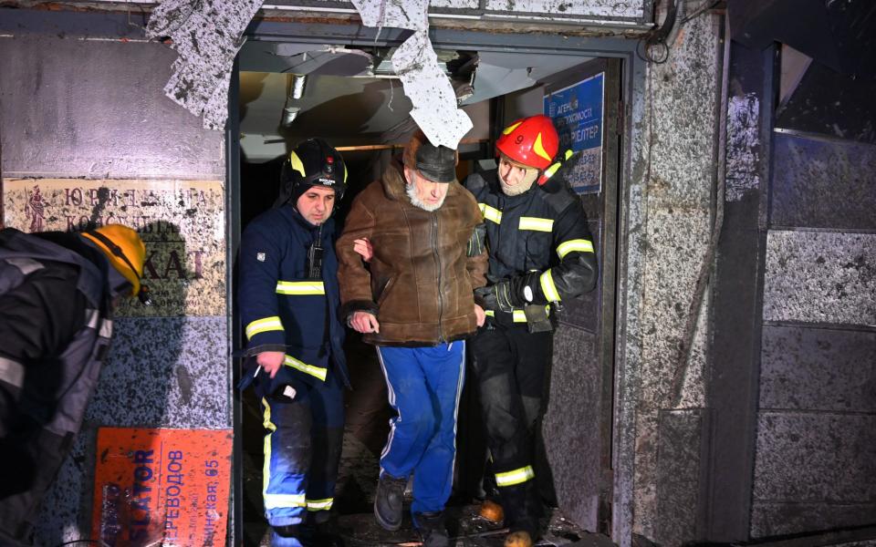 Firemen help a man out of a Kharkiv building damaged by a third wave of Russian missiles on Tuesday night