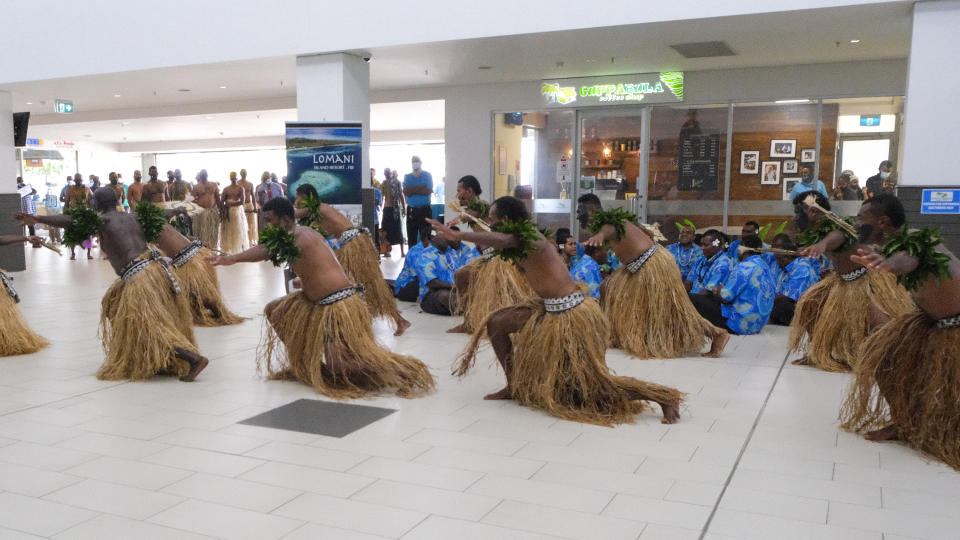 In this photo released by Tourism Fiji, guests receive a traditional Fijian welcome as they arrive at Nadi International airport in Fiji, Wednesday, Dec. 1, 2021. Fiji welcomed back its first tourists in more than 600 days on Wednesday after deciding to push ahead with reopening plans despite the threat posed by the omicron variant. (Bruce Rounds/Tourism Fiji via AP)