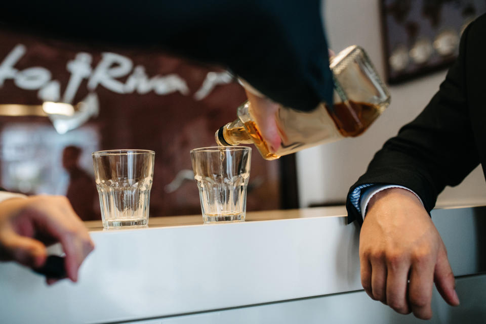 Person pouring a drink into two glasses at a wedding reception