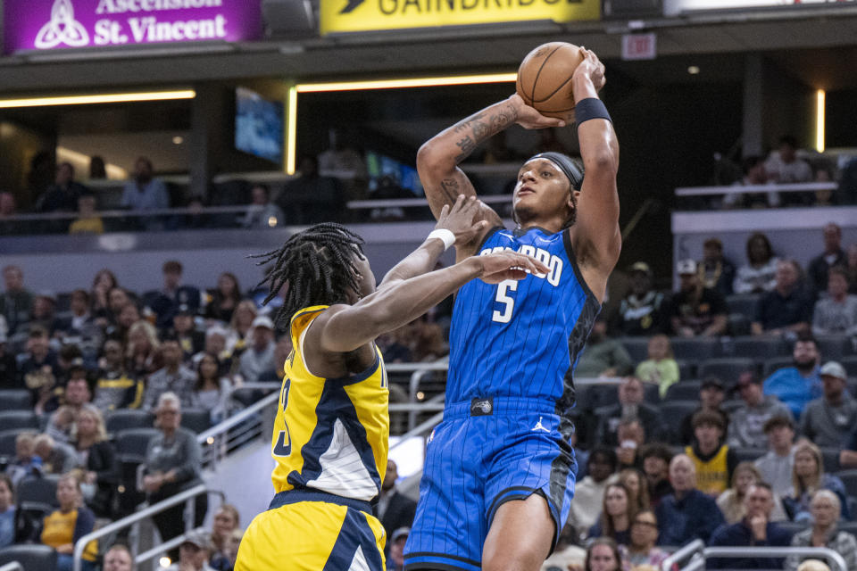 Orlando Magic forward Paolo Banchero (5) shoots while being defended by Indiana Pacers forward Aaron Nesmith, left, during the first half of an NBA basketball game in Indianapolis, Sunday, Nov. 19, 2023. (AP Photo/Doug McSchooler)