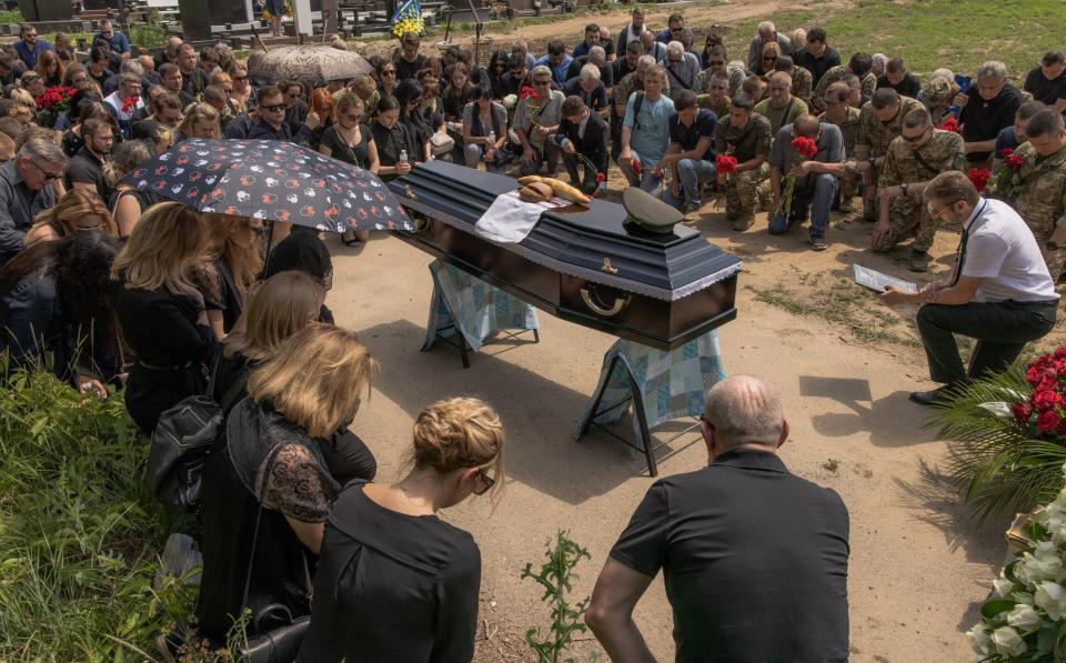 Relatives and friends of Anton Klitnyi, a fallen Ukrainian serviceman, kneel by his coffin