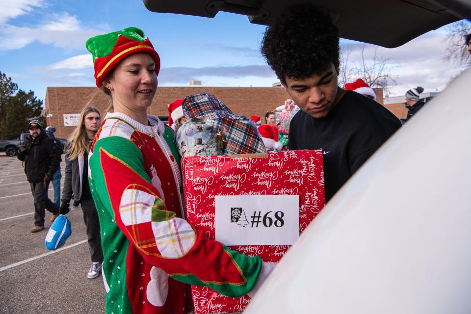 Rocky Mountain High School senior Gabriel Philippe, right, loads donations into a vehicle during the school's annual Adopt-A-Family distribution event on Saturday.