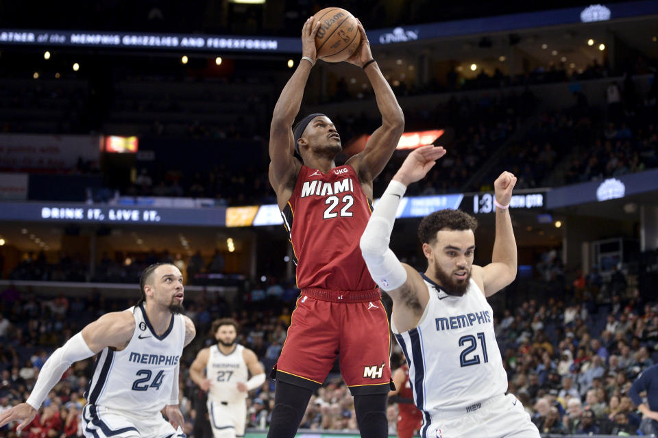 Miami Heat forward Jimmy Butler (22) shoots between Memphis Grizzlies guard Tyus Jones (21) and forward Dillon Brooks (24) in the second half of an NBA basketball game, Monday, Dec. 5, 2022, in Memphis, Tenn. (AP Photo/Brandon Dill)