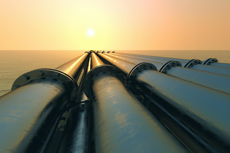 Pipelines over water at sunset.