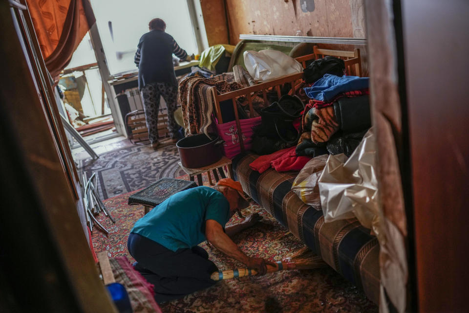 Mykola Telehyn, 74, and Ludmila Telehyna, 73, top, tidy up their apartment at a building damaged in an overnight missile strike in Sloviansk, Ukraine, Tuesday, May 31, 2022. (AP Photo/Francisco Seco)