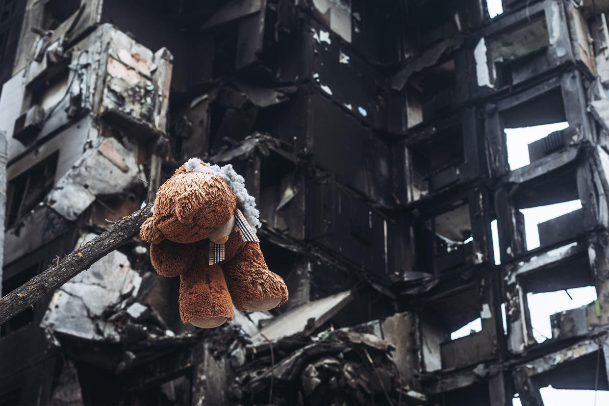 Teddy bear hanging from a tree in front of a bombed building; Ukraine; Bucha Diego Herrera Carcedo/Anadolu Agency via Getty Images