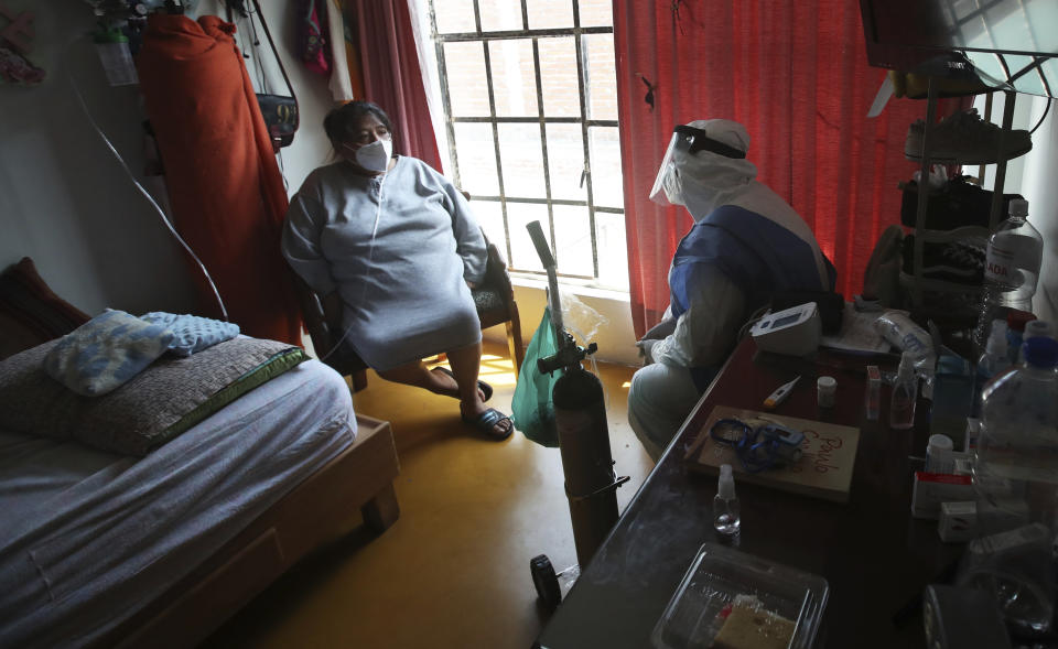 City worker Carlos Ruiz gives instruction to a COVID-19 patient after delivering a tank of oxygen to her home in the Iztapalapa borough of Mexico City, Friday, Jan. 15, 2021. The city offers free oxygen refills for COVID-19 patients. (AP Photo/Marco Ugarte)