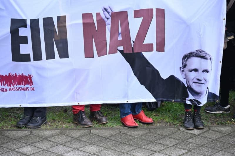 Demonstrators stand in front of the Justice Center holding a placard reading "Bjoern Hoecke is a Nazi" where the leading member of Germany's far-right Alternative for Germany (AfD) party Hoecke is standing for trial for allegedly using a banned Nazi slogan. Hendrik Schmidt/dpa