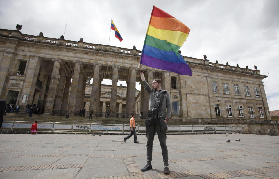 A man waves a banner in front of Colombia's Congress building where members of the LGBT gathered to show support for a proposed bill to legalize same sex marriage, being debating on by legislators, in Bogota, Tuesday, Nov. 27, 2012.  (AP Photo/Fernando Vergara)