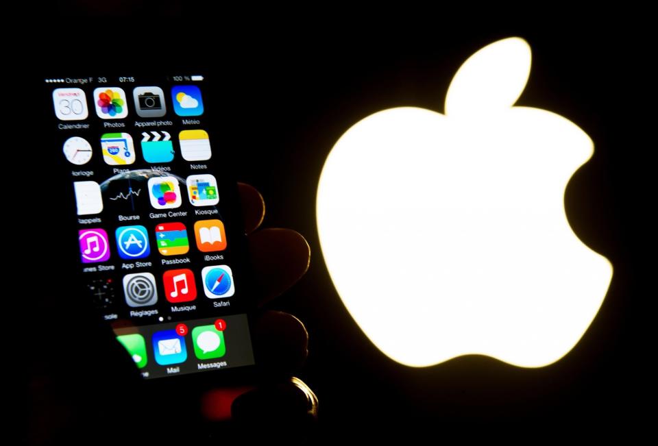 <em>Un iPhone, el teléfono móvil del gigante estadounidense Apple, junto al logo de la compañía. Foto: Philippe HUGUEN (AFP)</em>