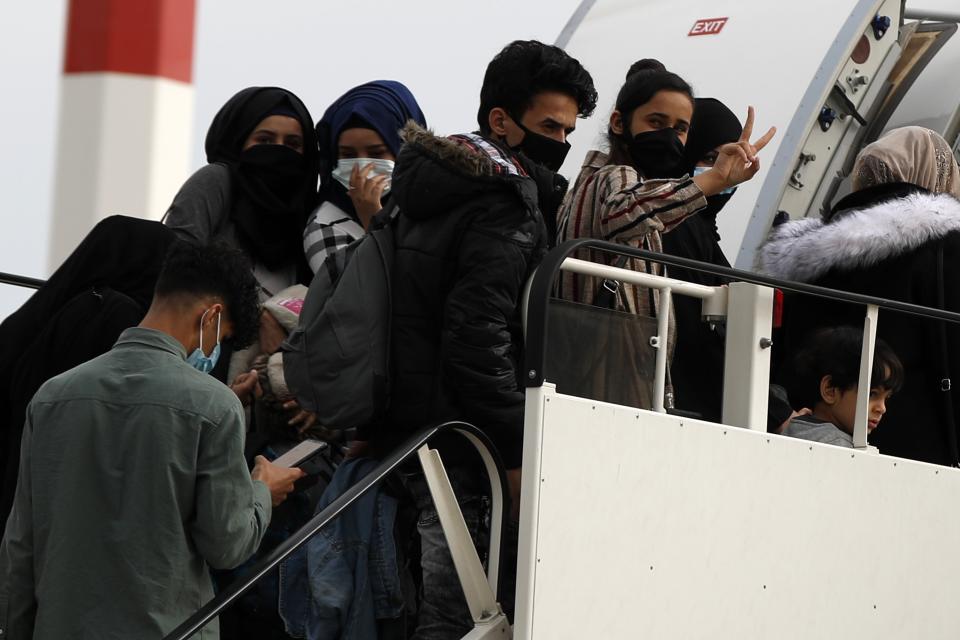 Migrants wearing face masks to prevent the spread of the coronavirus, board an airplane bound for Britain at the Eleftherios Venizelos International Airport in Athens, on Monday, May 11, 2020. Sixteen asylum-seeking minors and 34 migrants were relocated as part of a migrant reunification plan agreed between the two countries. (AP Photo/Thanassis Stavrakis)