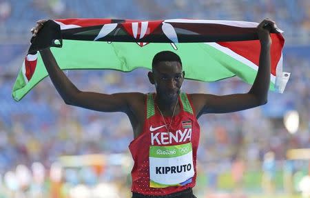 2016 Rio Olympics - Athletics - Final - Men's 3000m Steeplechase Final - Olympic Stadium - Rio de Janeiro, Brazil - 17/08/2016. Conseslus Kipruto (KEN) of Kenya holds his national flag after winning the gold. REUTERS/Ivan Alvarado