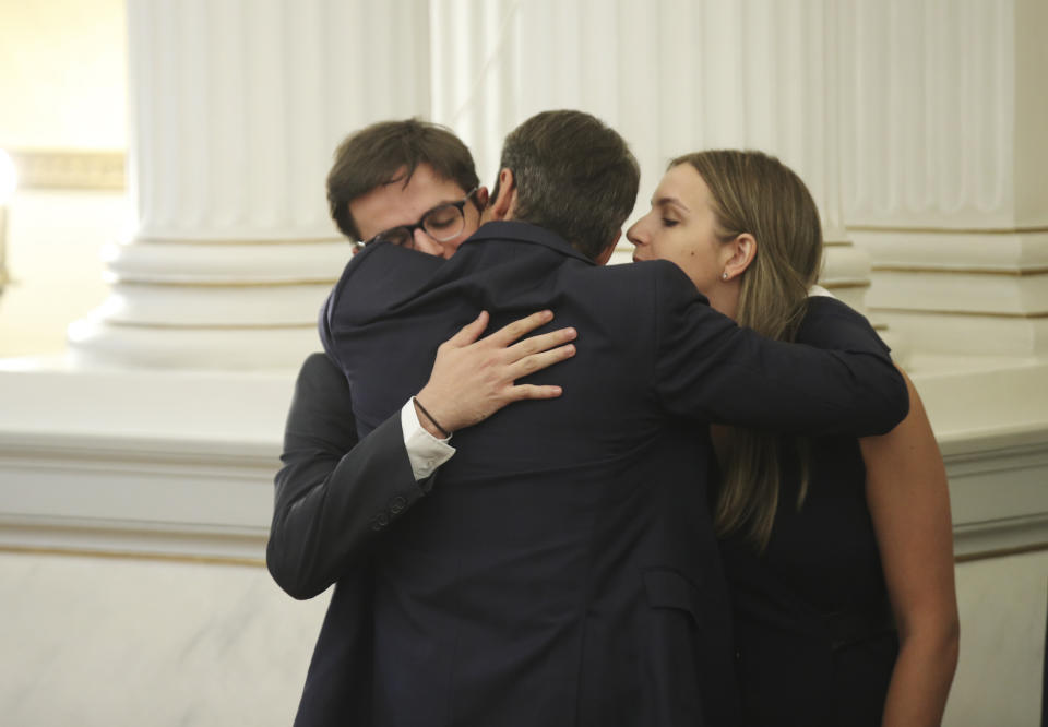 Greece's newly-elected prime minister Kyriakos Mitsotakis, bak on camera embraces his children, names not available, shortly after his swearing-in ceremony at the Presidential Palace in Athens, Monday, July 8, 2019. Mitsotakis' New Democracy party won 39.8% of the vote, giving him 158 seats in the 300-member parliament, a comfortable governing majority. (AP Photo/Petros Giannakouris)