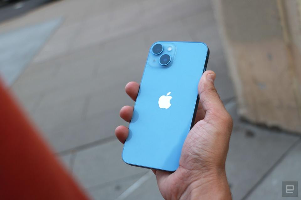 The iPhone 14 held in a hand with its rear cameras facing out.