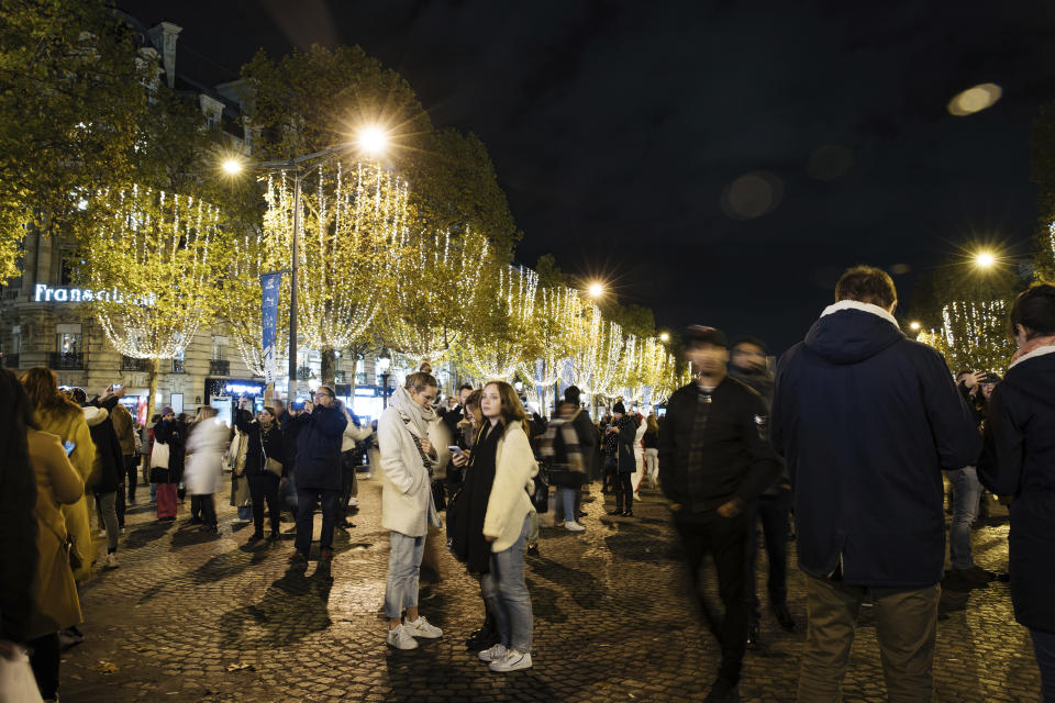 FILE - Spectators gather to attend the Champs Elysee Avenue illumination ceremony for the Christmas season, in Paris, Nov. 20, 2022. In cities across Europe, officials are wrestling with a choice this Christmas. Dim lighting plans to send a message of energy conservation and solidarity with citizens squeezed by both higher energy costs and inflation or let the lights blaze in a message of defiance after two years of pandemic-suppressed Christmas seasons, creating a mood that retailers hope loosen holiday purses. (AP Photo/Lewis Joly, File)