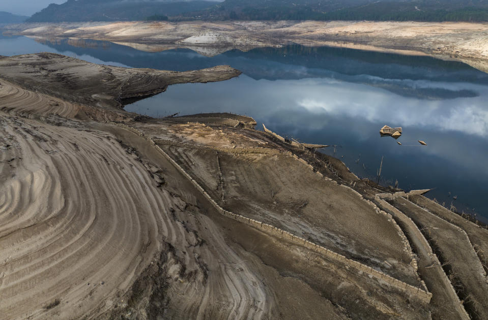 The roof of an old house, submerged three decades ago when a hydropower dam flooded the valley, is photographed emerged due to drought at the Lindoso reservoir, in northwestern Spain, Saturday, Feb. 12, 2022. With rainfall levels this winter at one-third of the average in recent years, large swaths of Spain are experiencing extreme or prolonged drought. (AP Photo/Emilio Morenatti)