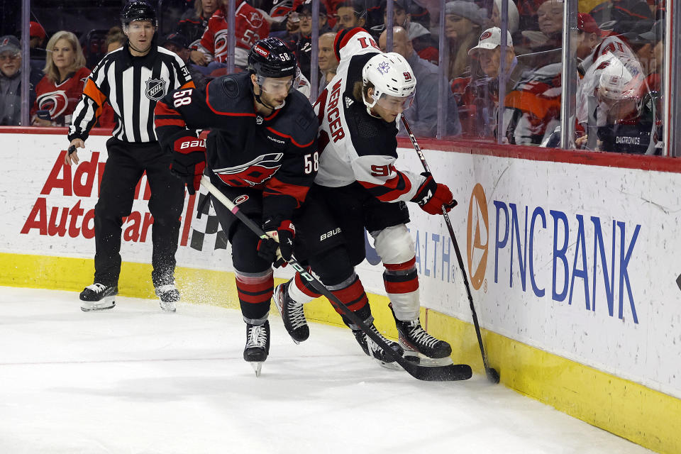 New Jersey Devils' Dawson Mercer (91) battles with Carolina Hurricanes' Michael Bunting (58) for the puck during the first period of an NHL hockey game in Raleigh, N.C., Thursday, Jan. 25, 2024. (AP Photo/Karl B DeBlaker)