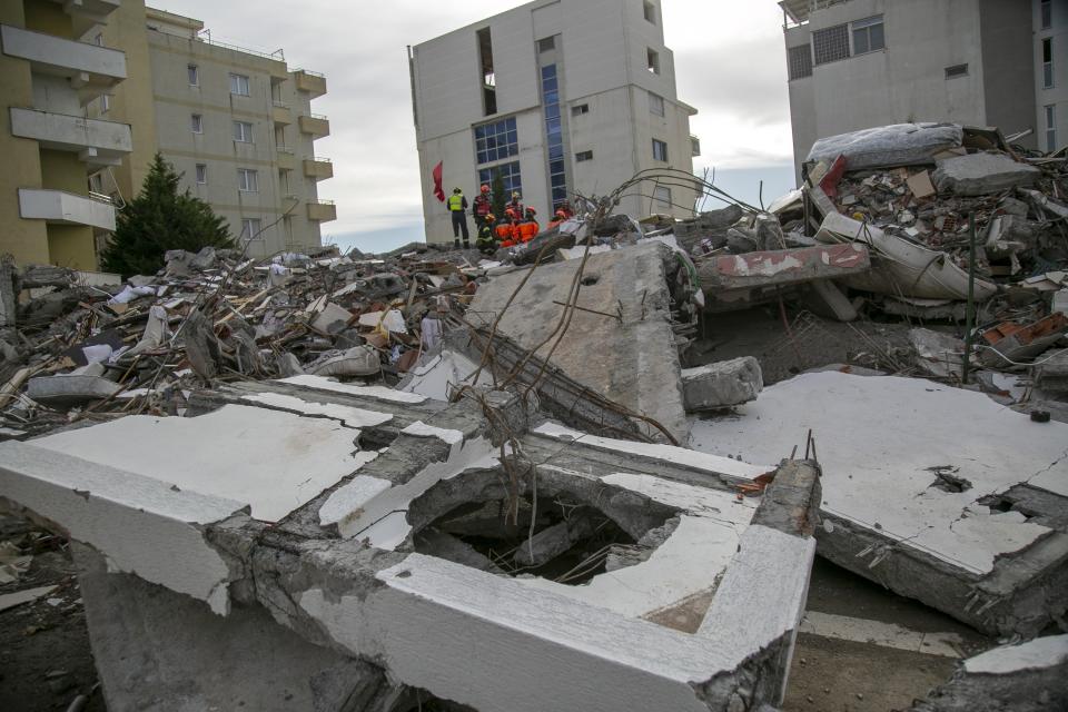 Rescuers stand on a collapsed building in Durres, western Albania, Friday, Nov. 29, 2019. The operation to find survivors and recover bodies from Albania's deadly earthquake was winding down Friday as the death toll climbed to 49. (AP Photo/Visar Kryeziu)