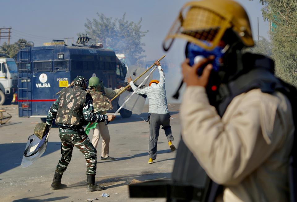 Policemen beat a protesting farmer, at the border between Delhi and Haryana state, Friday, Nov. 27, 2020. Thousands of agitating farmers in India faced tear gas and baton charge from police on Friday after they resumed their march to the capital against new farming laws that they fear will give more power to corporations and reduce their earnings. While trying to march towards New Delhi, the farmers, using their tractors, cleared concrete blockades, walls of shipping containers and horizontally parked trucks after police had set them up as barricades and dug trenches on highways to block roads leading to the capital. (AP Photo/Manish Swarup)