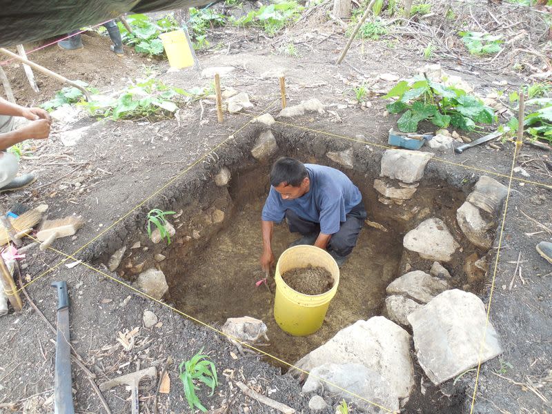 A member of the local community working with a team of archaeologists digs during excavations in Belize