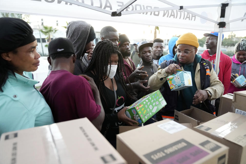 Migrants receive toys at an entry point, Tuesday, Dec. 20, 2022, in Tijuana, Mexico. The U.S. government made its plea in a filing a day after Chief Justice John Roberts issued a temporary order to keep the pandemic-era limits on migrants in place. (AP Photo/Marcio Jose Sanchez)