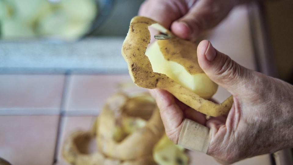 mature hands peeling a potato