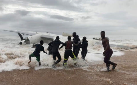 People pull the wreckage of a propeller-engine cargo plane after it crashed in the sea near the international airport in Ivory Coast's main city, Abidjan - Credit: REUTERS