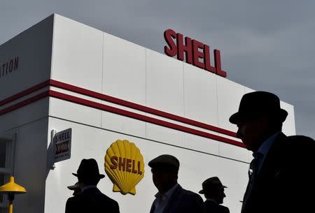 Visitors and car enthusiasts are silhouetted against a building with Shell signage attached during the Goodwood Revival historic motor racing festival in Goodwood, near Chichester in south England, Britain, in this September 11, 2015 file photo. REUTERS/Toby Melville/Files