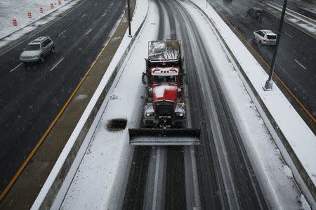 A snowplow truck and commuters travel on Rt. 395 as the snow begins to fall in Washington January 22, 2016. REUTERS/Jonathan Ernst