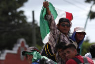 Central American migrants making their way to the U.S. in a large caravan wave a Mexican flag as they arrive to Tapachula, Mexico, after a truck driver gave them a free ride, Sunday, Oct. 21, 2018. Despite Mexican efforts to stop them at the Guatemala-Mexico border, about 5,000 Central American migrants resumed their advance toward the U.S. border Sunday in southern Mexico. (AP Photo/Moises Castillo)