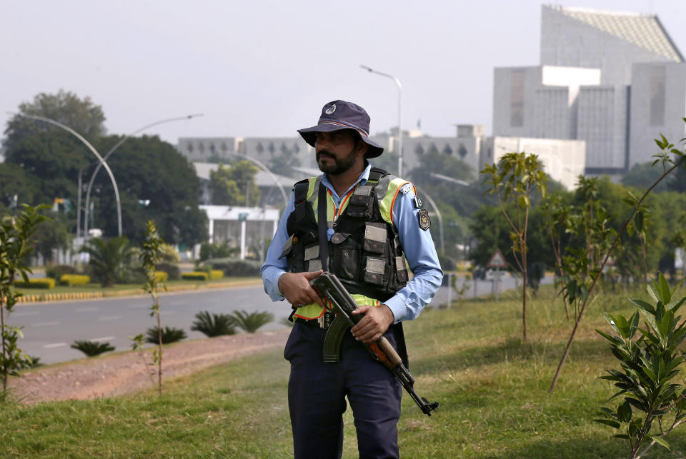 A police officer stands guard on a main road for security during the British Royal couple visit in Islamabad, Pakistan, Tuesday, Oct. 15, 2019. Britain's Prince William and his wife Kate kicked off a five-day tour of Pakistan on Tuesday, amid much fanfare and tight security. (AP Photo/Anjum Naveed)