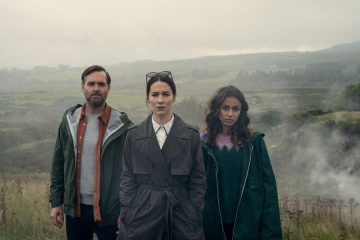 Three people stand in the countryside in Bodkin.