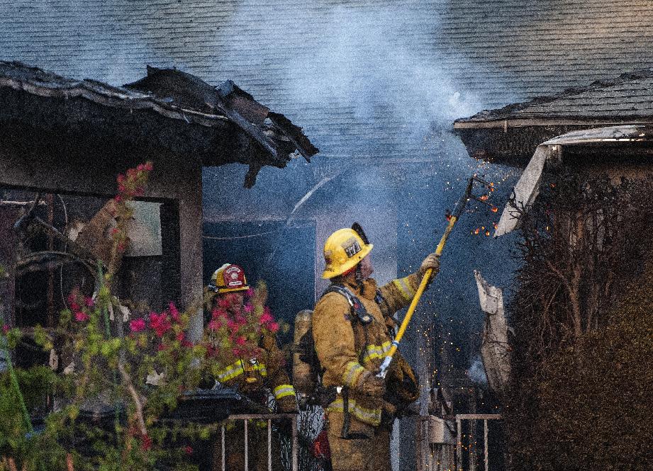 Orange County Fire Authority firefighters mop up hot spots after a house fire on Wednesday, Jan. 8, 2014 in Santa Ana, Calif. Authorities say two people have been killed and four others injured in the early morning fire at a group home for developmentally disabled adult women. Orange County Fire Authority spokesman Steve Concialdi says the blaze broke out at about 5:45 a.m. Wednesday in the residential neighborhood of Santa Ana. Concialdi says the home's caretaker, a 71-year-old woman, was critically injured while attempting to rescue residents from the single-story, four-bedroom home. (AP Photo/The Orange County Register, Bruce Chambers) MAGS OUT; LOS ANGELES TIMES OUT